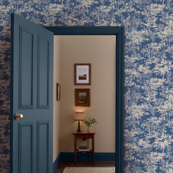 Blick durch eine geöffnete, blaue Zimmertür in einen Flur. Die Wand ist mit einer blau gemusterten Tapete gestaltet.