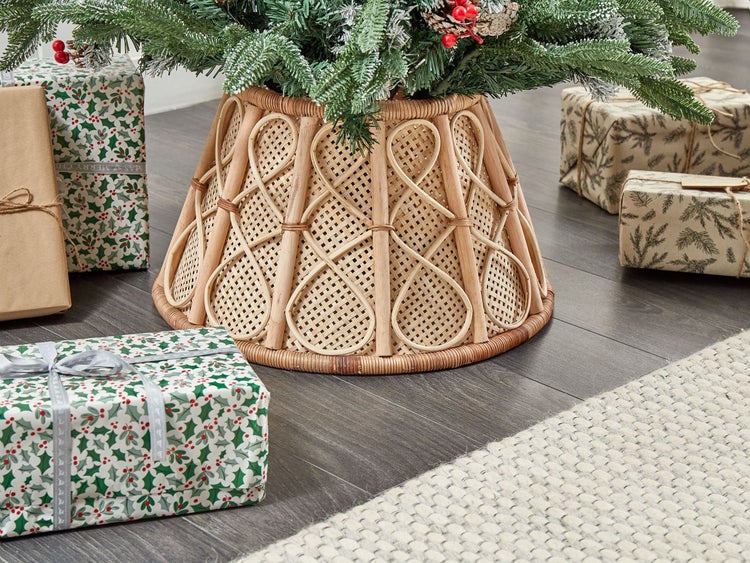 Weihnachtliche Szene mit Weihnachtsbaumständer aus Rattan und verpackten Geschenken