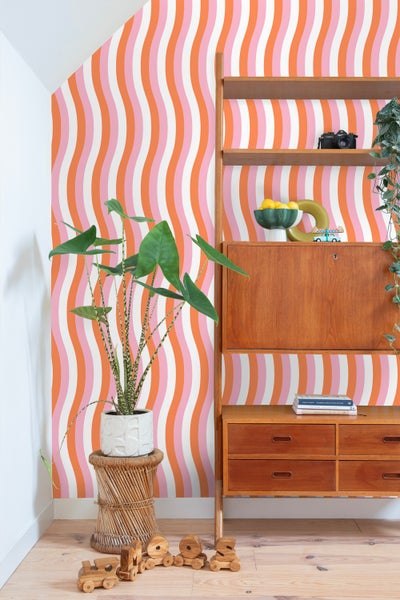 Szene mit Zimmerpflanze in gestreiftem Übertopf, gerippter Kerze und Dekoration auf einem Tisch