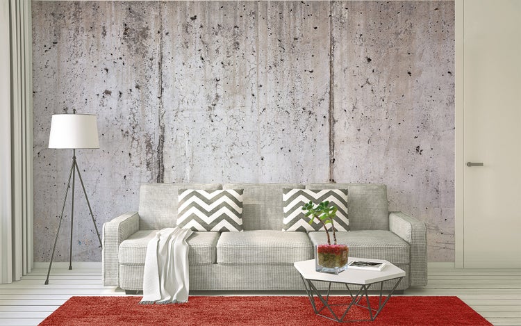 Fototapete in Beton-Optik in einem modern eingerichteten Wohnzimmer mit Sofa, Teppich, Stehlampe und Couchtisch.