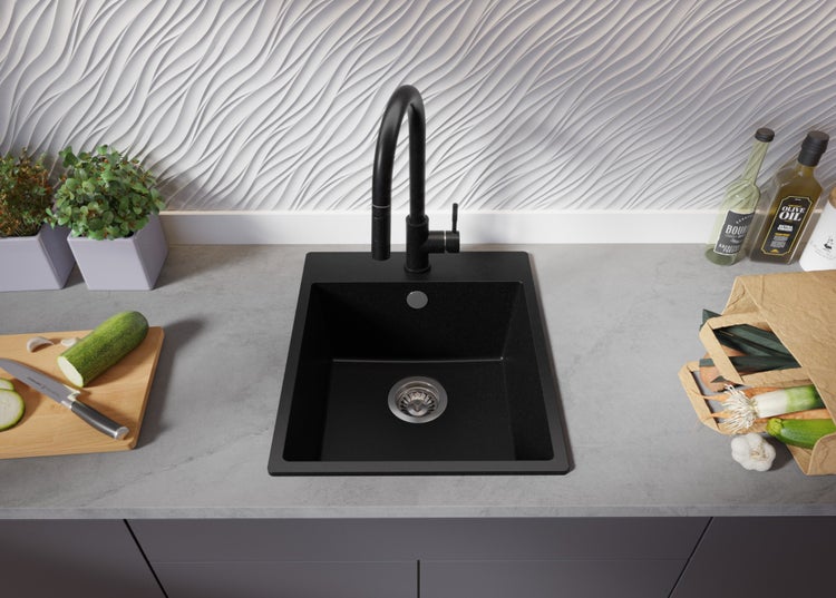 Schwarzes Küchenspülbecken mit Armatur auf einer Arbeitsplatte mit Lebensmitteln