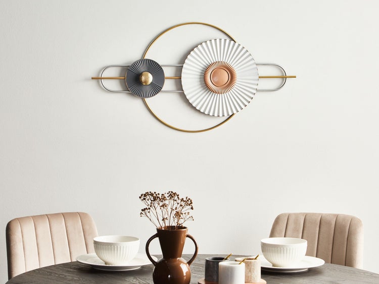 Dekorative Wandkunst mit geometrischen Formen über einem Esstisch mit Geschirr und Stühlen.