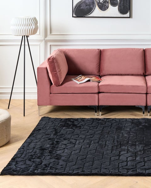 Wohnzimmer mit schwarzem Teppich, Sofa und Stehlampe