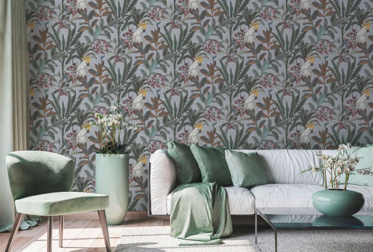 Wohnzimmer mit Vliestapete im tropischen Design mit Papageien und floralem Muster, dekoriert mit modernem Sofa, Sessel und Zimmerpflanzen.