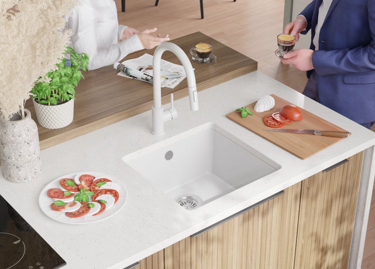 Küchenspüle auf einer Küchentheke mit Armatur, Schneidebrett, Zutaten und Dekoration