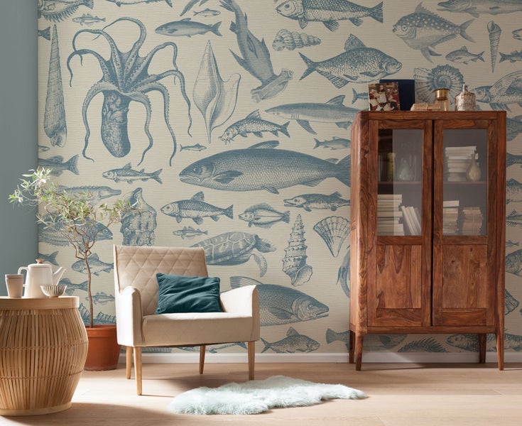Wohnzimmer mit Sessel, Tisch, Vitrine und Tapete mit Meeresmotiven