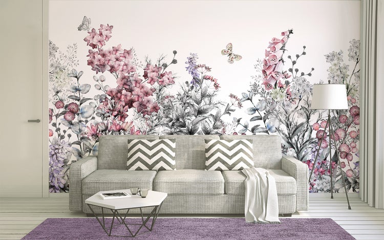 Vlies-Fototapete mit floralem Muster, Blumen und Schmetterlingen in einem hellen Wohnzimmer hinter einem Sofa.