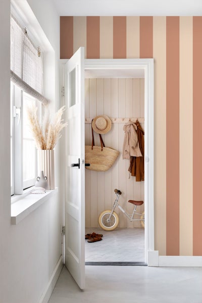 Hell gestalteter Flur mit vertikal gestreifter Tapete, offener weißer Tür und Blick in eine strukturierte Garderobe mit Holzpaneelen.