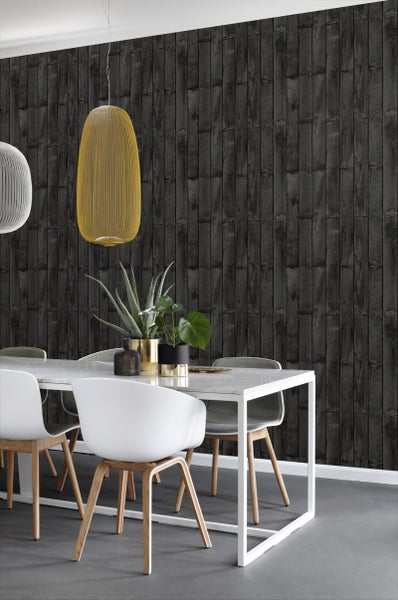 Esszimmer mit Esstisch, Stühlen und einer Wand mit Holzoptik-Tapete