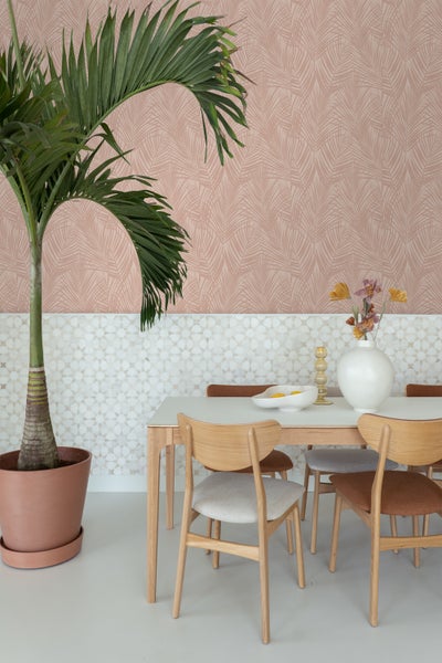 Helles Esszimmer mit Esstisch, Stühlen, Topfpflanze und gemusterter Tapete