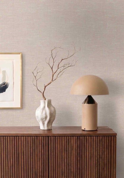 Strukturierte Tapete in Leinenoptik an einer Wand hinter einem Sideboard aus Holz mit Lamellenfront, Lampe und Vase.