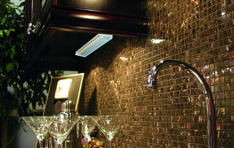 Küchenszene mit Unterbauleuchte, Wasserhahn, Mosaikfliesen und Cocktailgläsern