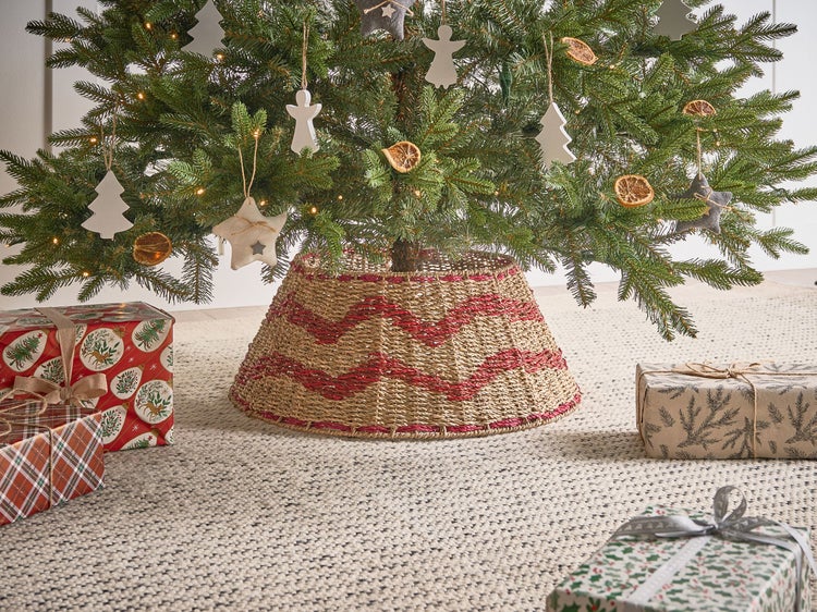 Weihnachtsbaum mit geflochtenem Baumständer und Dekorationen sowie Geschenken