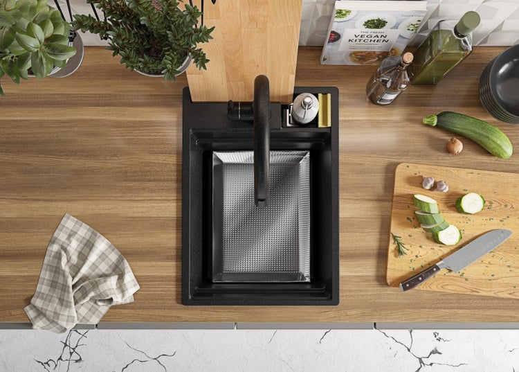 Küchenspüle mit Abtropfschale, Armatur, Spülmittelspender, Schneidebrett, Gemüse, Kochbuch und Geschirrtuch auf einer Küchentheke