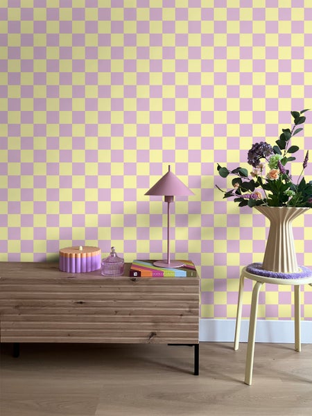 Zimmer mit Schachbrettmuster-Tapete, Kommode, Lampe und Blumenstrauß