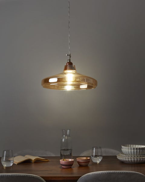 Hängelampe aus Glas über einem Esstisch mit Geschirr