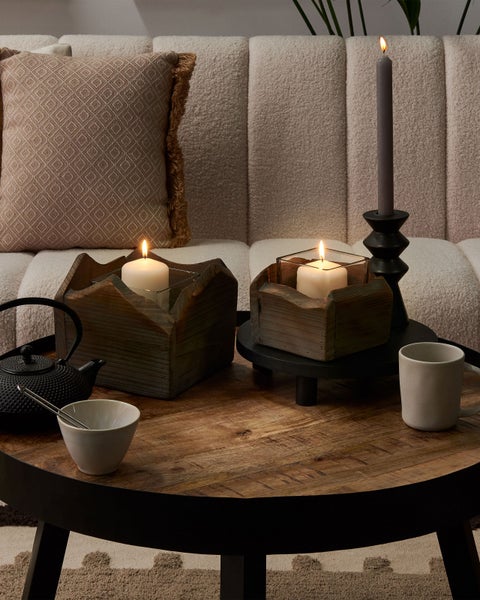 Dekoratives Wohnzimmerarrangement mit Kerzen, Teekanne und Geschirr auf einem Couchtisch