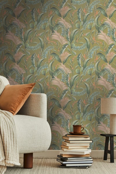 Wohnzimmer mit tropischer Blättertapete, Sofa und Bücherstapel