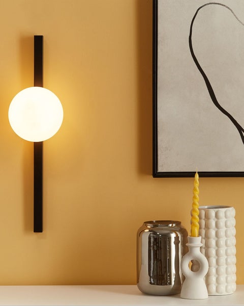 Wandleuchte mit Glaskugel und Dekoration auf einem Tisch.