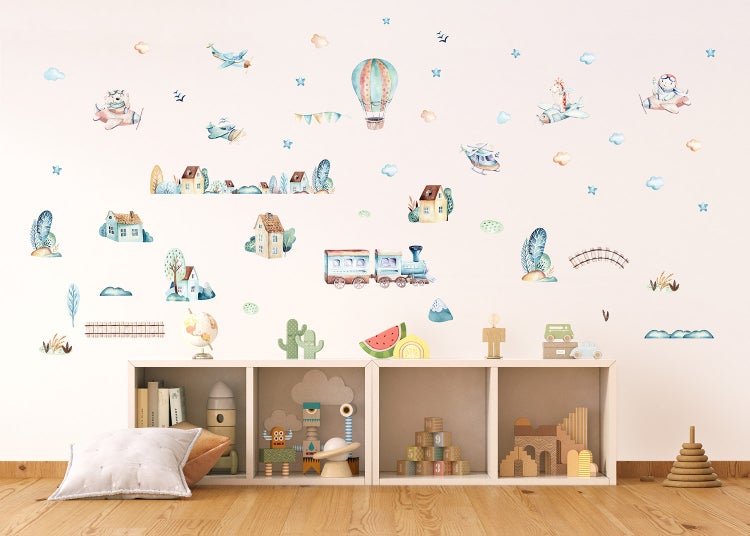 Wandtattoo Kinderzimmer mit Motiven von Zug, Heißluftballon und Flugzeugen über einem Regal mit Holzspielzeug in einem hellen, geordneten Raum.