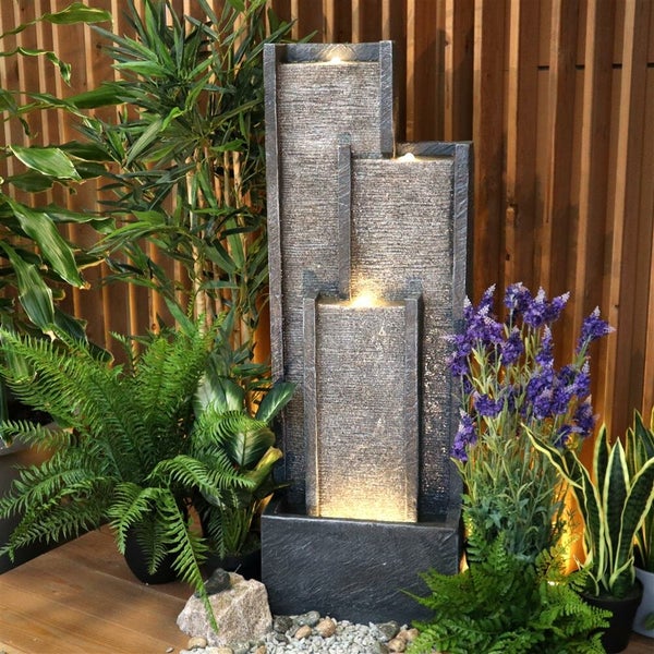 Dekorativer Zimmerbrunnen mit Pflanzen auf einem Holzboden