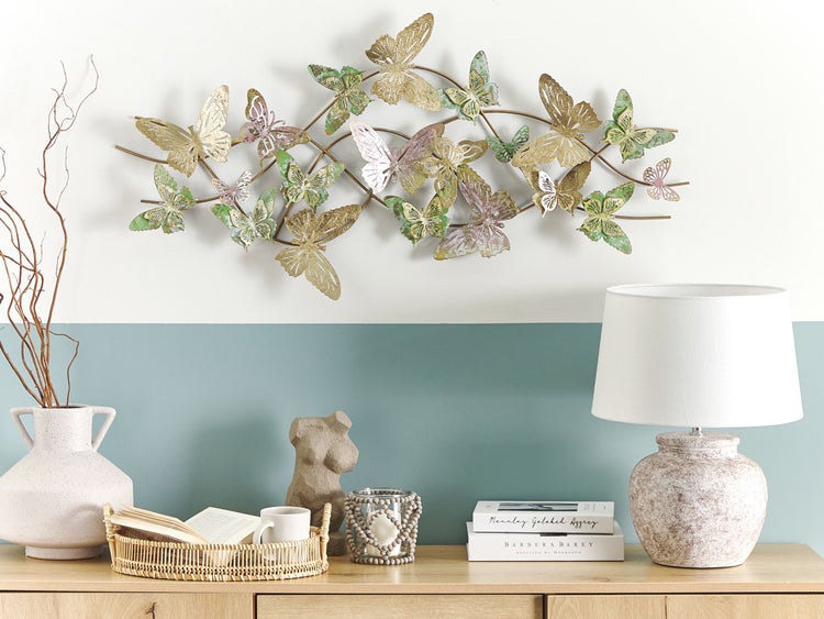 Dekoratives Wohnambiente mit Schmetterlingswanddeko, Lampe, Vase und Accessoires auf einem Holzschrank
