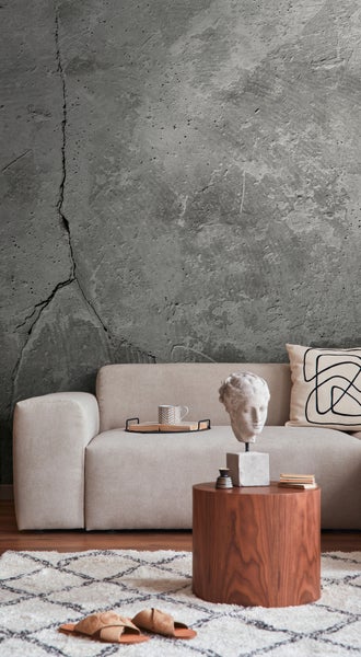 Fototapete in Betonoptik mit Rissen hinter einem hellen Sofa in einem modernen Wohnzimmer.