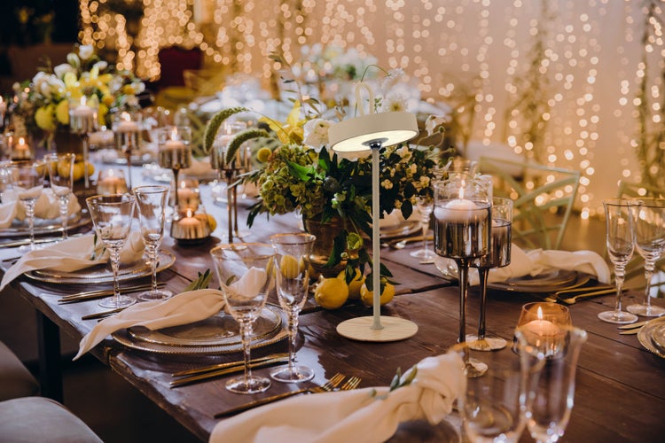 Festlich gedeckter Tisch mit Geschirr, Gläsern, Kerzen und Blumenschmuck für eine Feier