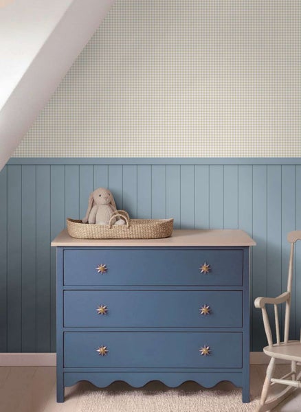 Kinderzimmer mit karierter Tapete, blauer Wandvertäfelung, Kommode mit drei Schubladen und Stoffhase im Weidenkorb.