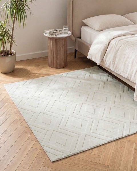 Teppich mit geometrischem Rautenmuster in einem modern eingerichteten Schlafzimmer mit Parkettboden.