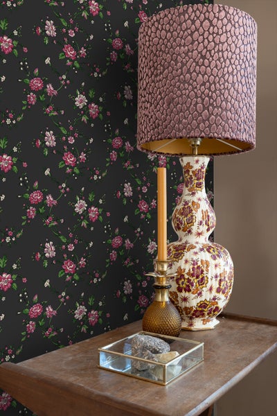 Dekoratives Interieur mit Tischlampe, Kerze und geblümter Tapete