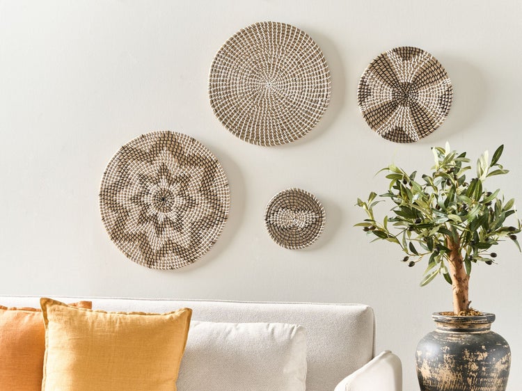 Dekorative Wandkörbe und ein Olivenbaum auf einer Wohnzimmerkommode