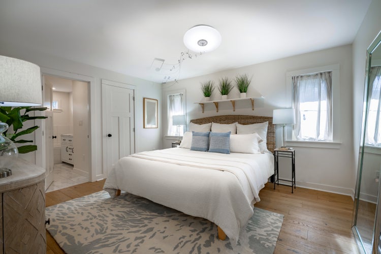 Helles Schlafzimmer mit Doppelbett, Rattan-Kopfteil und dekorativem Teppich