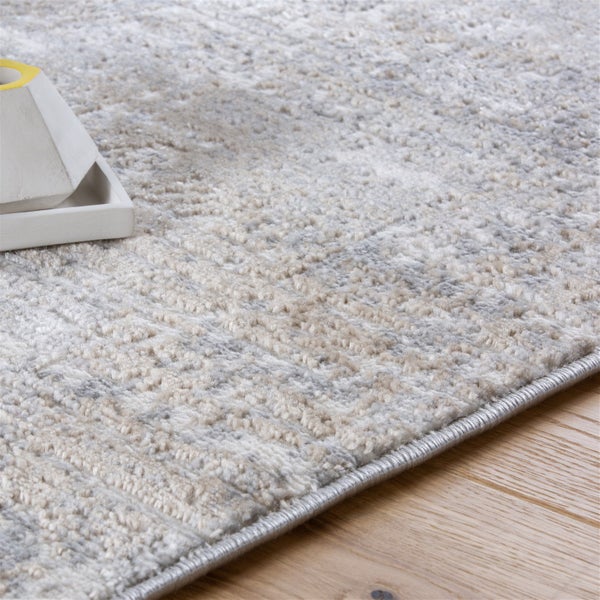 Strukturierter Teppich in Grau und Beige mit kurzem Flor auf Holzboden, Nahaufnahme der Kantenverarbeitung.
