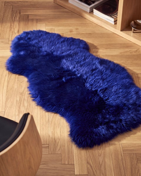Flauschiges Kunstfell in Tierfellform auf einem Holzboden in einem Wohnraum.