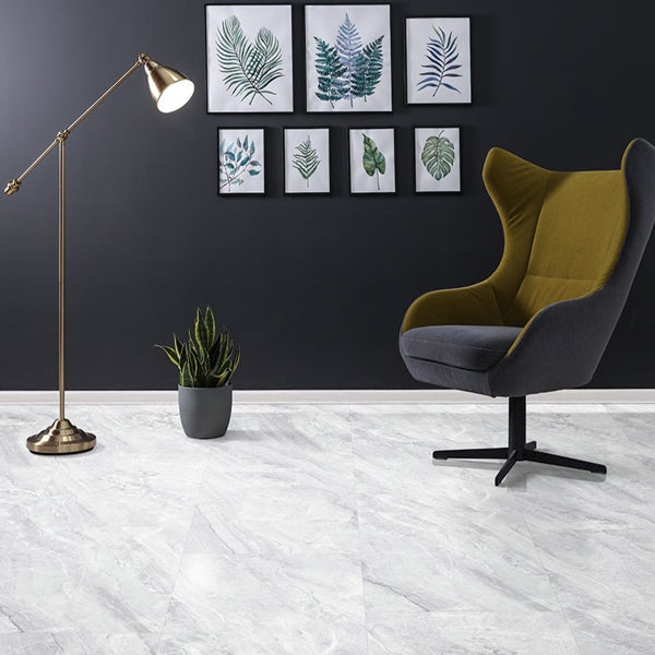 Innenraum mit Bodenfliesen in Marmoroptik, Stehlampe, Sessel und Wanddekoration mit Pflanzenmotiven.