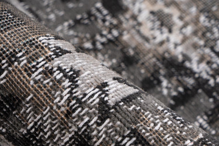Nahaufnahme der Struktur eines gewebten Teppichs mit grauem, schwarzem und weißem Muster.