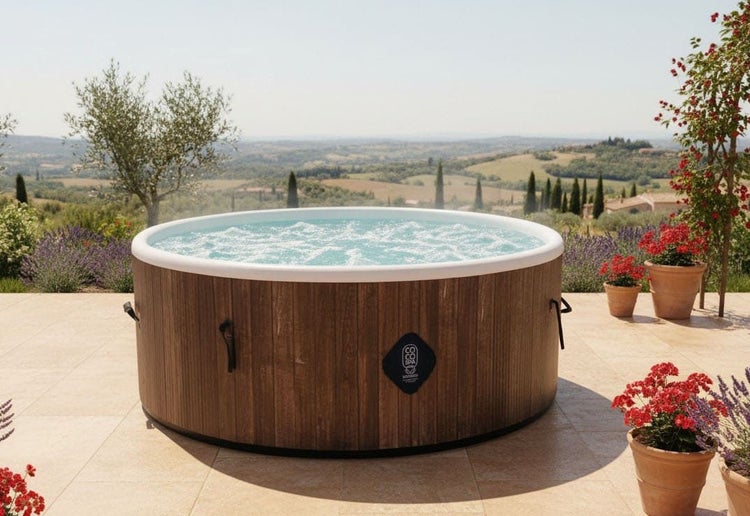 Runder, aufblasbarer Whirlpool in Holzoptik mit sprudelndem Wasser auf einer hellen Terrasse mit weitem Landschaftsblick.