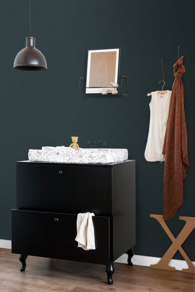 Zimmeransicht mit schwarzer Kommode, Wickelauflage, Lampe und Dekoration