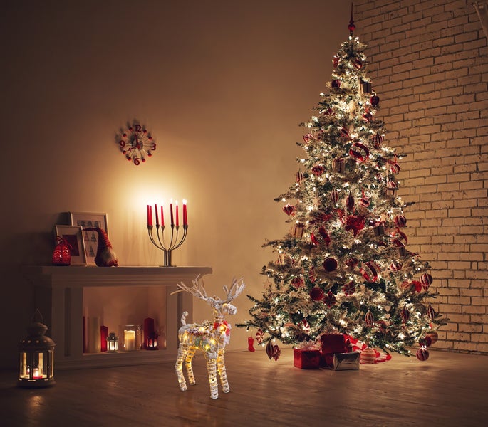 Weihnachtliche Wohnzimmerdekoration mit Weihnachtsbaum, leuchtendem Rentier, Kamin und Kerzen