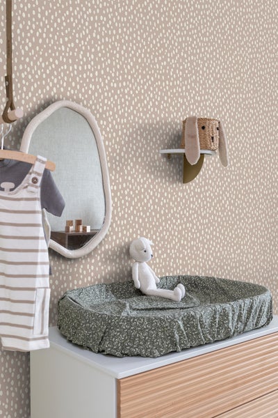Kinderzimmer mit Wickelkommode, Spiegel, Regal und Dekoration vor einer gemusterten Tapete