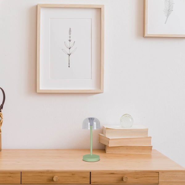 Dekorative Tischleuchte auf einem Schreibtisch mit Bilderrahmen und Büchern