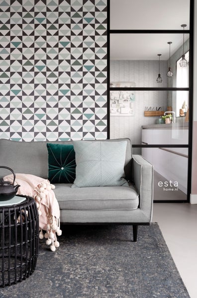 Wohnraum mit Sofa, Kissen und geometrischer Tapete