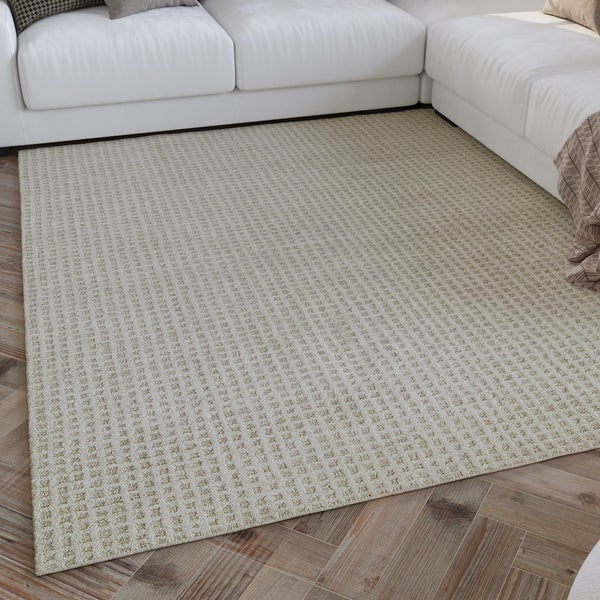 Strukturierter Teppich mit feinem Karomuster in einem hellen Wohnzimmer vor einem weißen Sofa auf Holzparkett.