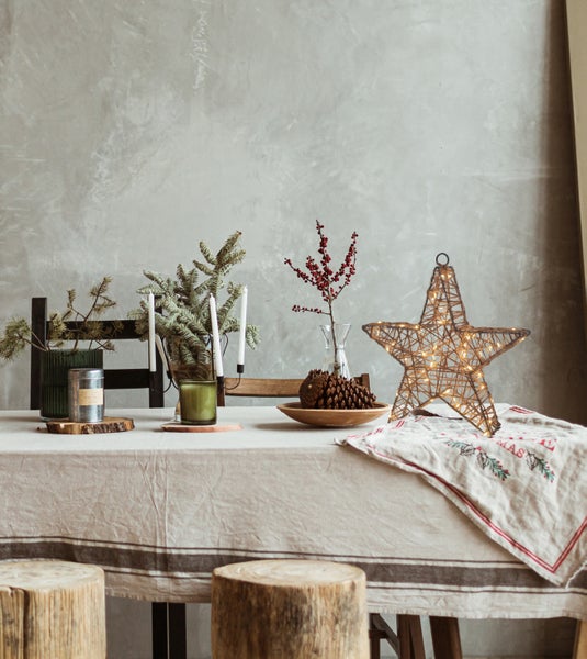 Festlich gedeckter Tisch mit Dekorationsartikeln wie Sternleuchte, Kerzen und Tannenzweigen
