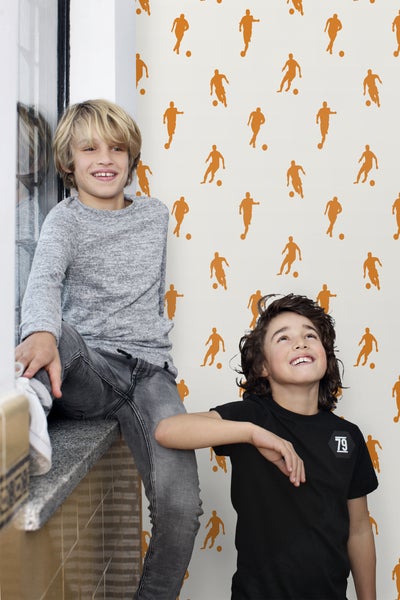 Zwei Jungen vor einer Wand mit Fußballmotiven.