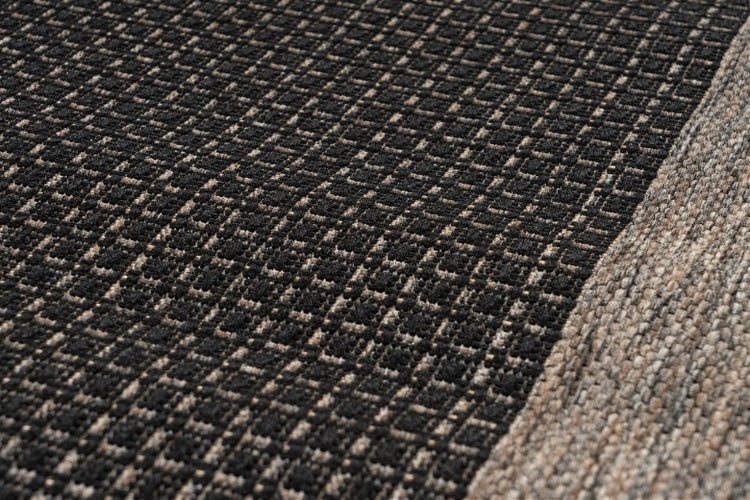 Nahaufnahme eines gewebten Teppichs mit strukturiertem Karomuster und abgesetztem Rand.