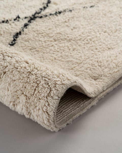 Detailansicht eines flauschigen Hochflor-Teppichs mit geometrischem Muster und weicher Oberfläche.