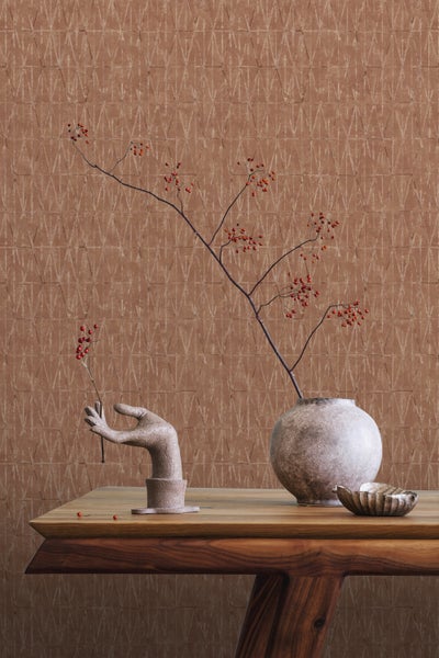 Dekorative Szene mit brauner gemusterter Tapete, Holztisch, Vase, Handskulptur und Zweigen mit roten Beeren.