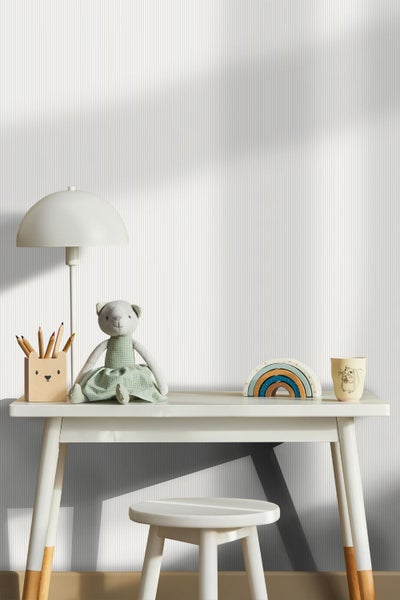 Vliestapete mit feinem vertikalem Streifenmuster im Kinderzimmer hinter einem Sideboard mit Aufbewahrungsboxen und einem Kissen.